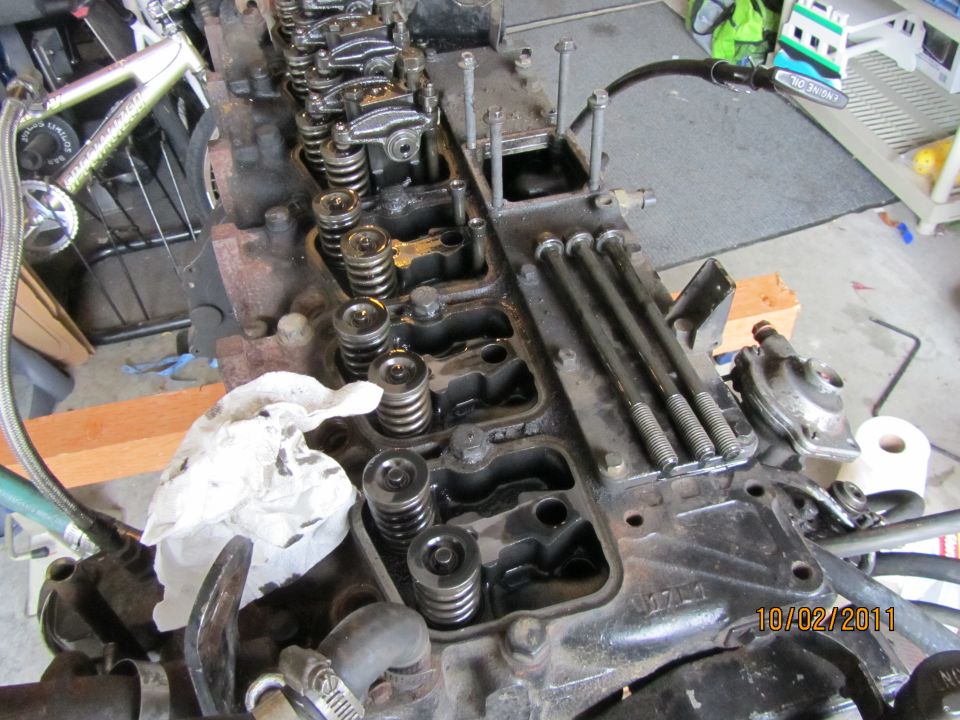 Engine block with valve train components visible, some bolts removed. Date stamp 10/02/2011