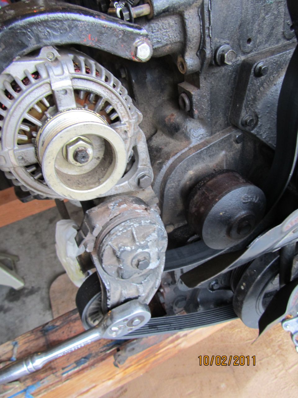 Engine alternator and belt tensioner with a socket wrench on the tensioner pulley