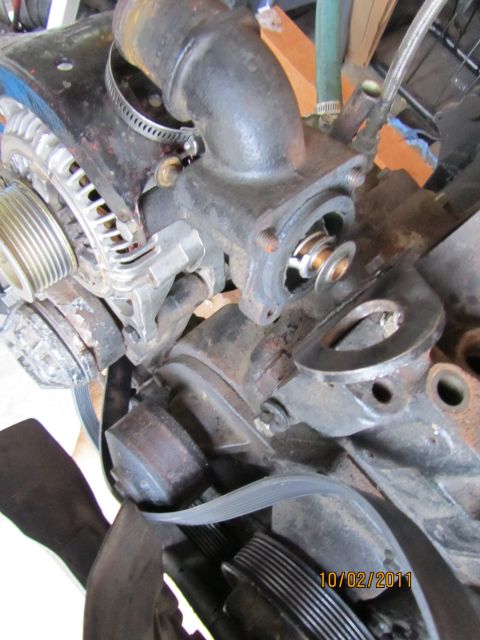 1984 Ford Bronco - Close-up view of an engine's water pump and thermostat housing, showing the removed thermostat.