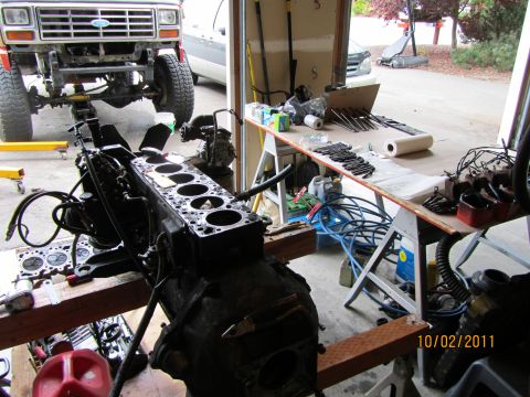 1984 Ford Bronco - Disassembled engine block and front end of a Ford Bronco in a garage setting.