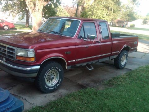 1992 Ford F-150 - This red Ford F-150 pickup truck is shown from the front three-quarter view, parked outside.