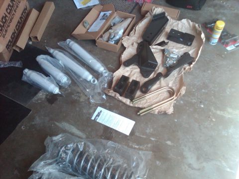 1992 Ford F-150 - Various suspension parts for a vehicle are spread across a garage floor.