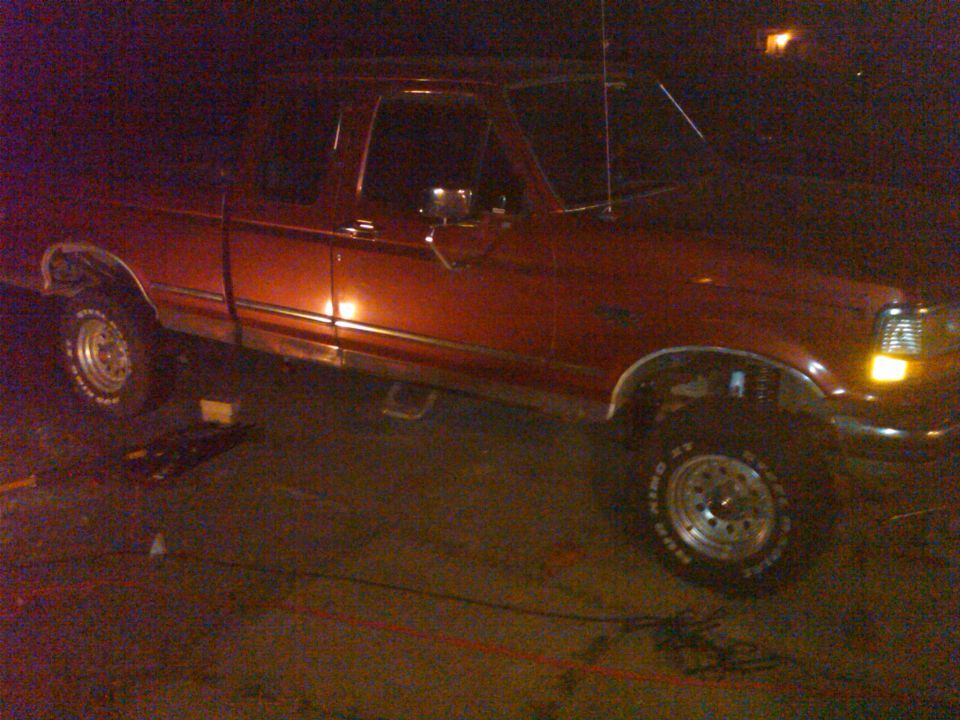 Red 1992 Ford F-150 pickup truck, side view, with a lift kit installed