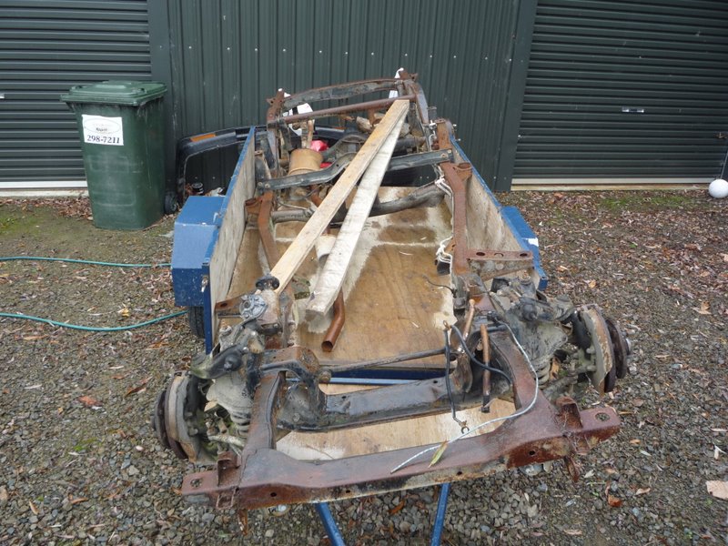 Car chassis on trailer, front view. Some wooden supports are visible
