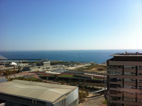 1987 Suzuki Samurai - Coastal city scene with buildings and the ocean. Watermark visible.