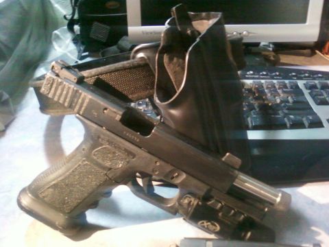 1996 Ford Bronco - A pistol with a tactical light and extended magazine sits in a holster on a desk next to a keyboard.