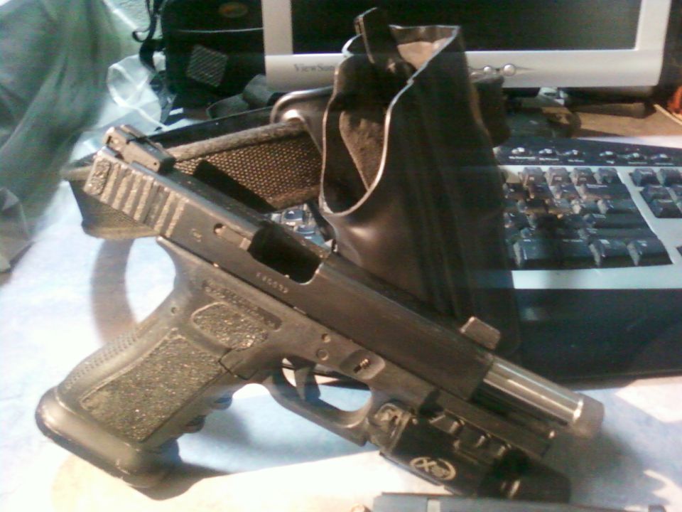 Pistol with extended magazine and tactical light in a holster on a desk