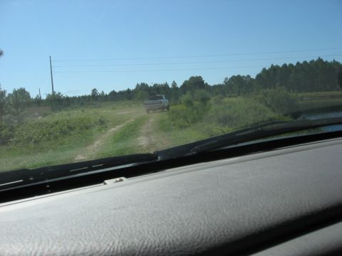 1994 Ford Bronco - View from inside a vehicle looking out at a pickup truck on a rural dirt road.