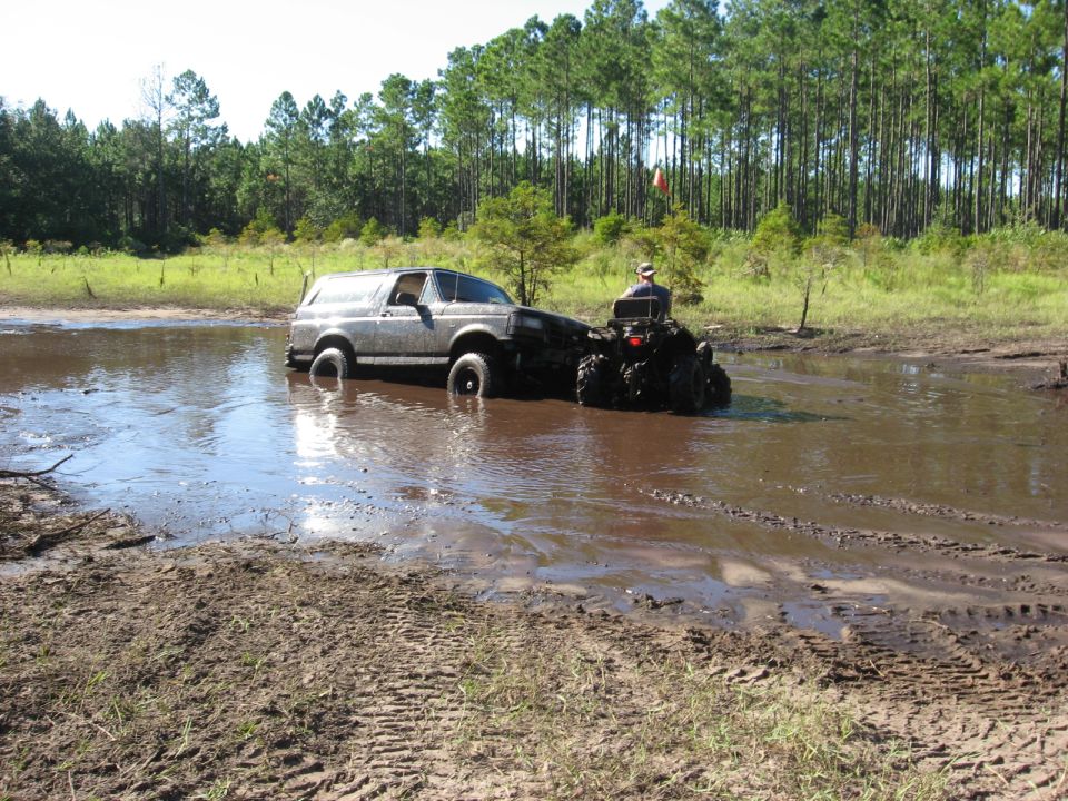Gray Ford Bronco stuck in mud, being pulled by an ATV
