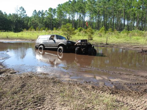 1994 Ford Bronco - A 1994 Ford Bronco is stuck in a mud pit, with another off-road vehicle partially submerged beside it.