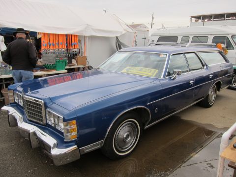 1991 Ford LTD Crown Victoria - Blue station wagon with a "FOR SALE" sign in the windshield parked at an outdoor market.