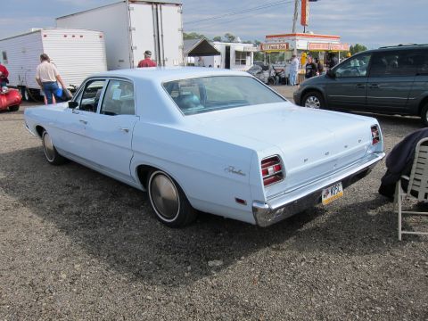 1991 Ford LTD Crown Victoria - This light blue sedan, identified as a 1969 Ford, is seen from the rear at an outdoor event.