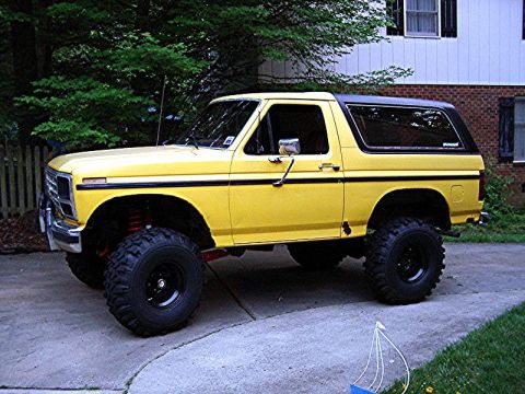 1985 Ford Bronco - This lifted 1985 Ford Bronco is parked on a driveway in front of a house.