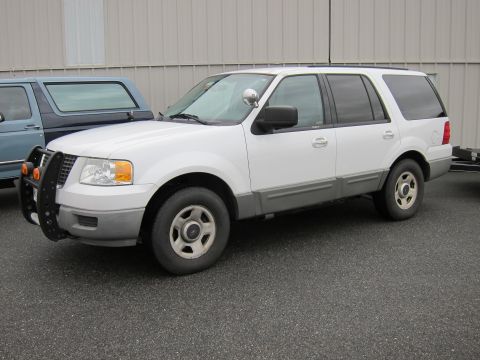 1991 Ford LTD Crown Victoria - White Ford Expedition with a push bar is parked next to a blue pickup truck.