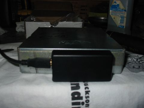 1992 Ford Bronco - Engine control unit with an adapter and cable connected, resting on a surface.