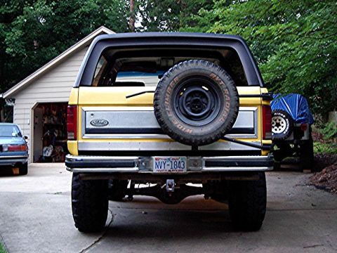 1985 Ford Bronco - Rear view of a yellow 1985 Ford Bronco, a spare tire mounted on the tailgate and a license plate.