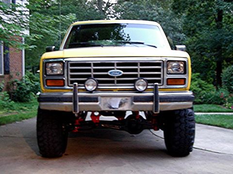1985 Ford Bronco - Front view of a yellow Ford Bronco, showing its grille and bumper.