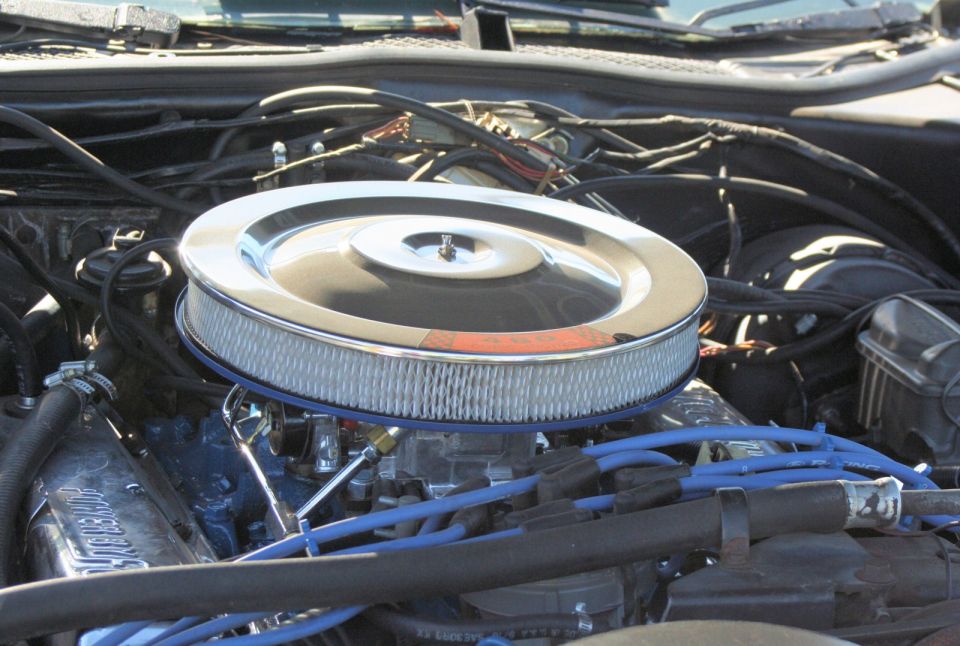 Close-up of an engine bay showing a chrome air cleaner assembly and blue spark plug wires