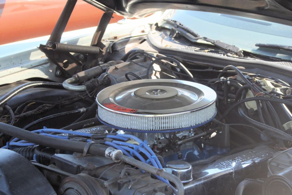 Engine bay of a 1976 Ford Ranchero with a chrome air cleaner and blue spark plug wires