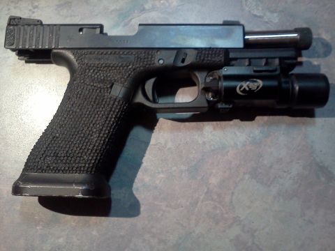 1996 Ford Bronco - A black pistol with a tactical light mounted underneath the barrel is displayed against a textured surface.