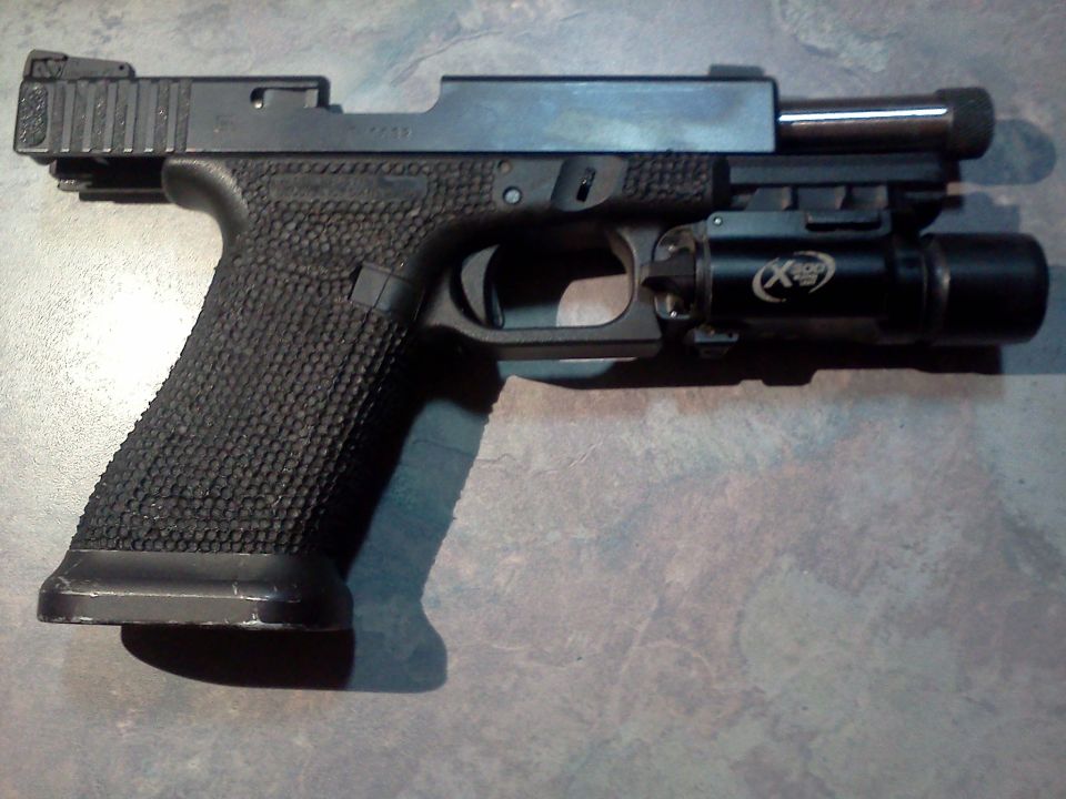 Black pistol with textured grip and attached tactical light, shown from the side