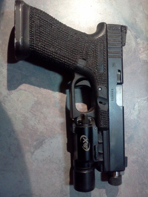 1996 Ford Bronco - A pistol with a textured grip and an attached tactical light is shown against a textured surface.