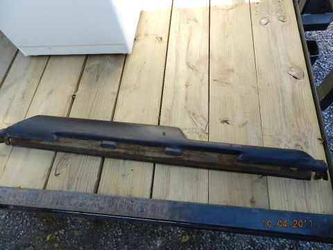 1978 Ford Bronco - A black plastic trim piece with a metal backing is shown resting on wooden planks. The date 10 04 2011 is visible in the lower right corner.