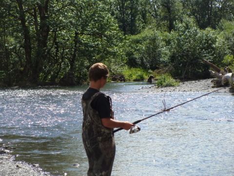 1986 Chevrolet Blazer - A person fishes in a river while bears are visible in the background.