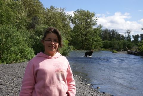 1986 Chevrolet Blazer - A young girl stands on a riverbank while a bear walks through the water in the background.