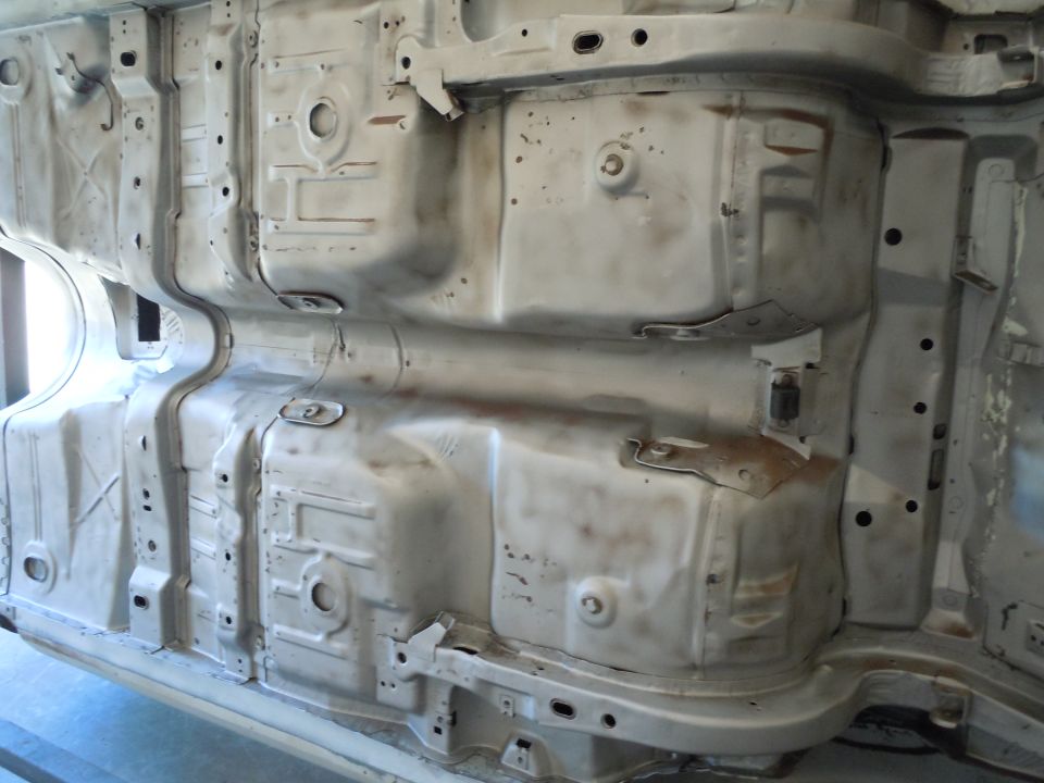 Undercarriage of a car, showing metal frame and some rust spots