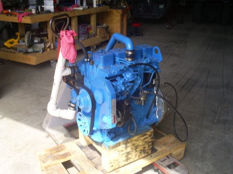 1992 Ford Bronco - A bright blue engine sits on a wooden pallet in a workshop setting.