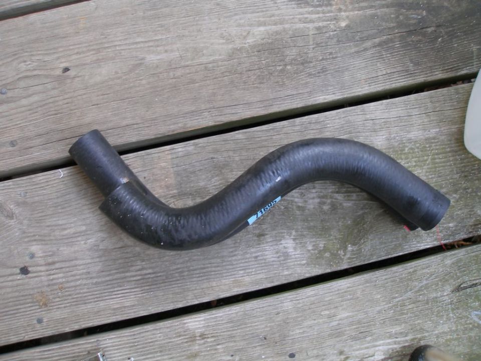 Black rubber radiator hose with blue label, lying on wooden planks