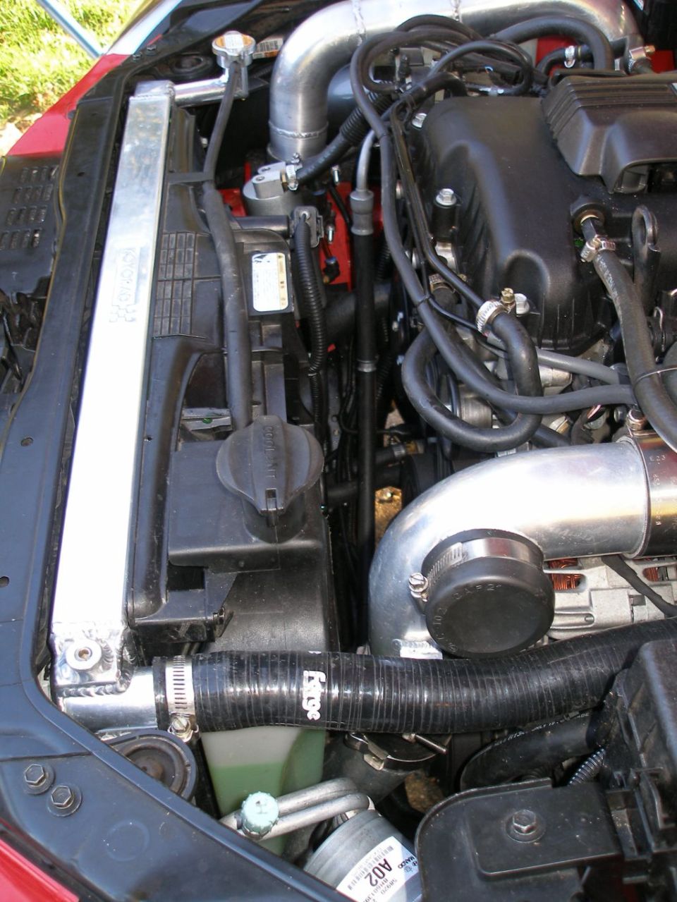Engine bay showing a Koyo radiator, aluminum piping, and engine components. Black hoses are visible