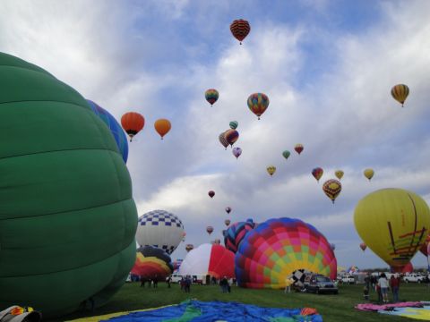 1993 Ford Taurus - A field filled with hot air balloons, some inflated and ready for flight, others on the ground under a cloudy sky.
