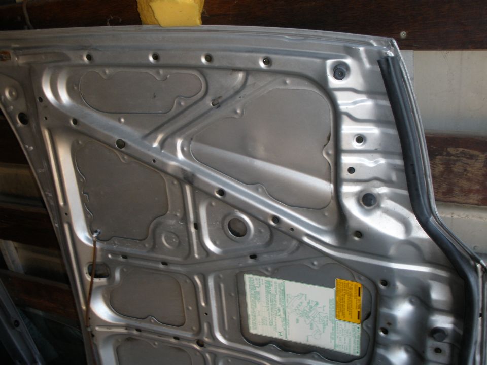 Inside of a removed sheet-metal car door panel with a green factory label