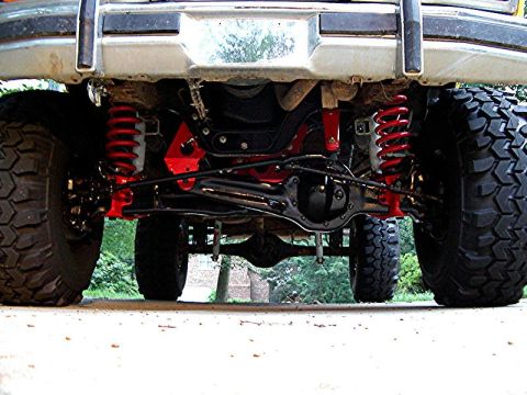 1985 Ford Bronco - The undercarriage of a heavily modified SUV, bright red suspension parts and aggressive tires.