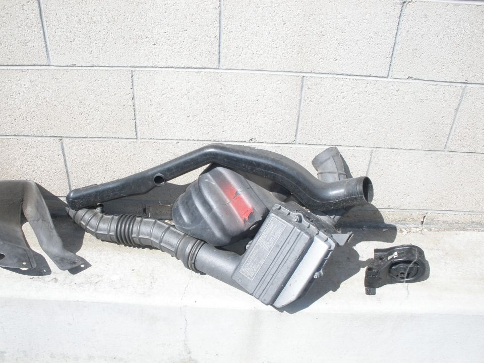 Air intake components including hoses and a filter box are laid out on a concrete surface