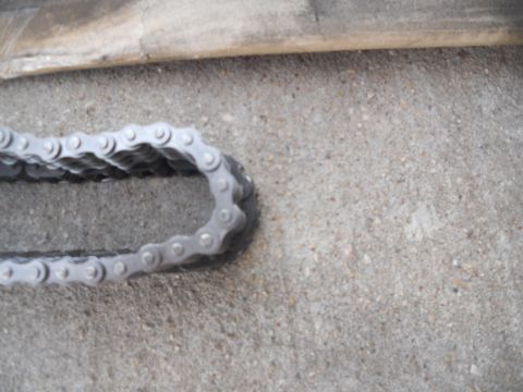 1991 Ford Bronco - A close-up view of a metal chain, likely a component from a vehicle or machinery, resting on a concrete surface.