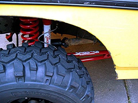 1985 Ford Bronco - Close-up of a yellow vehicle's suspension system and a large off-road tire.