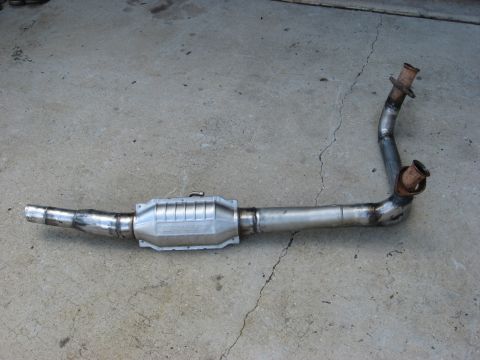 1994 Ford Bronco - A catalytic converter and exhaust pipe assembly lies on a concrete surface.