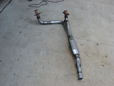 1994 Ford Bronco - Exhaust pipe assembly with catalytic converter shown on a concrete surface.