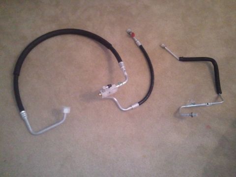 1994 Ford Bronco - Three AC hoses and associated fittings are laid out on a carpeted surface.