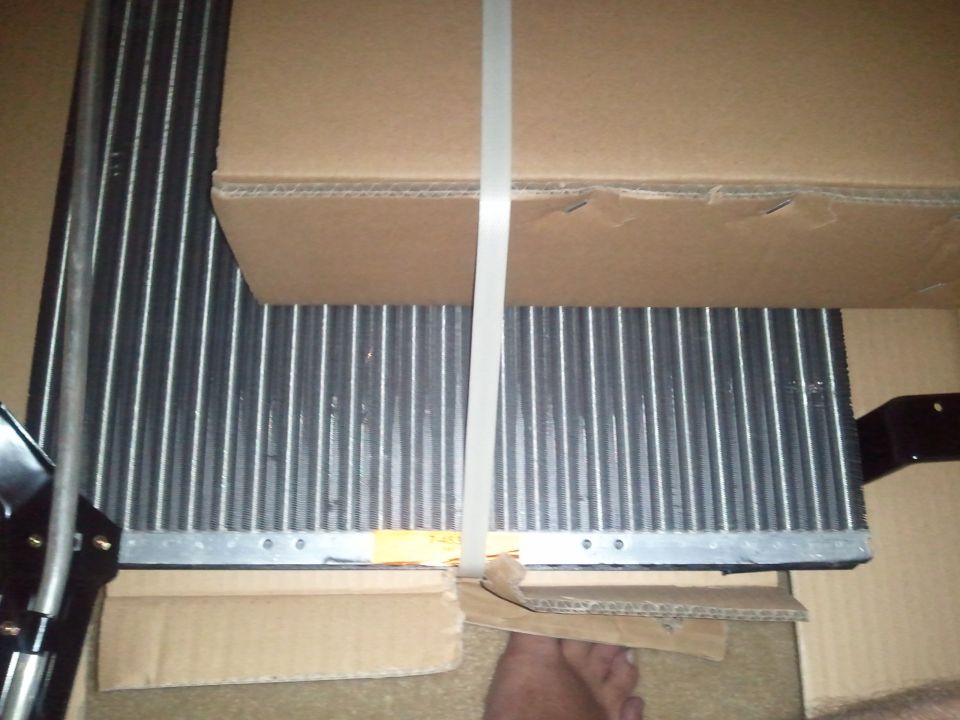 Car AC condenser in a cardboard box, strapped with white plastic