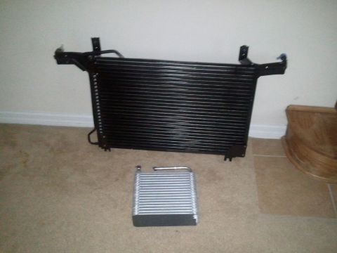 1994 Ford Bronco - Two car AC system parts, a condenser and an evaporator, are displayed on a carpeted floor.