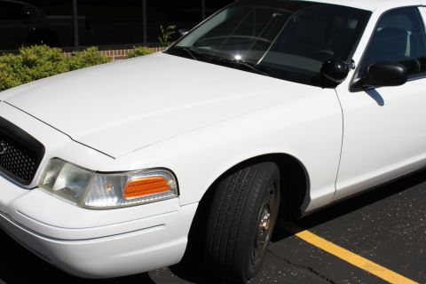 2003 Ford Crown Victoria - Front corner view of a white 2003 Ford Crown Victoria, showing the headlight and fender.
