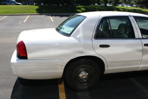 2003 Ford Crown Victoria - Rear passenger side view of a white sedan parked in a lot.