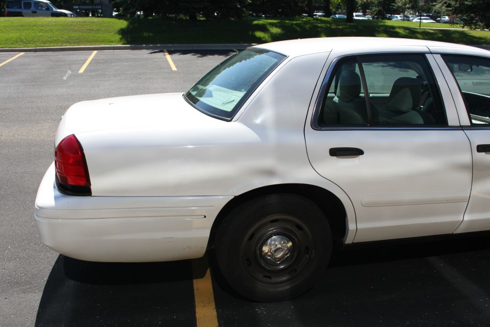 White sedan parked in a lot, showing the rear quarter panel and side