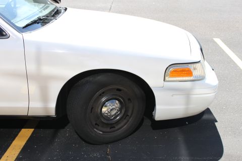 2003 Ford Crown Victoria - Front passenger side view of a white 2003 Ford Crown Victoria, showing the fender and wheel.