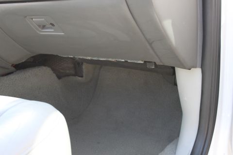 2003 Ford Crown Victoria - Interior view of a car's passenger footwell and dashboard, showing carpeting and trim.