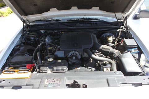 2003 Ford Crown Victoria - The engine bay of a 2003 Ford Crown Victoria is shown with the hood raised, revealing the engine components and battery.